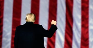 Trump raising his fist in front of an American flag