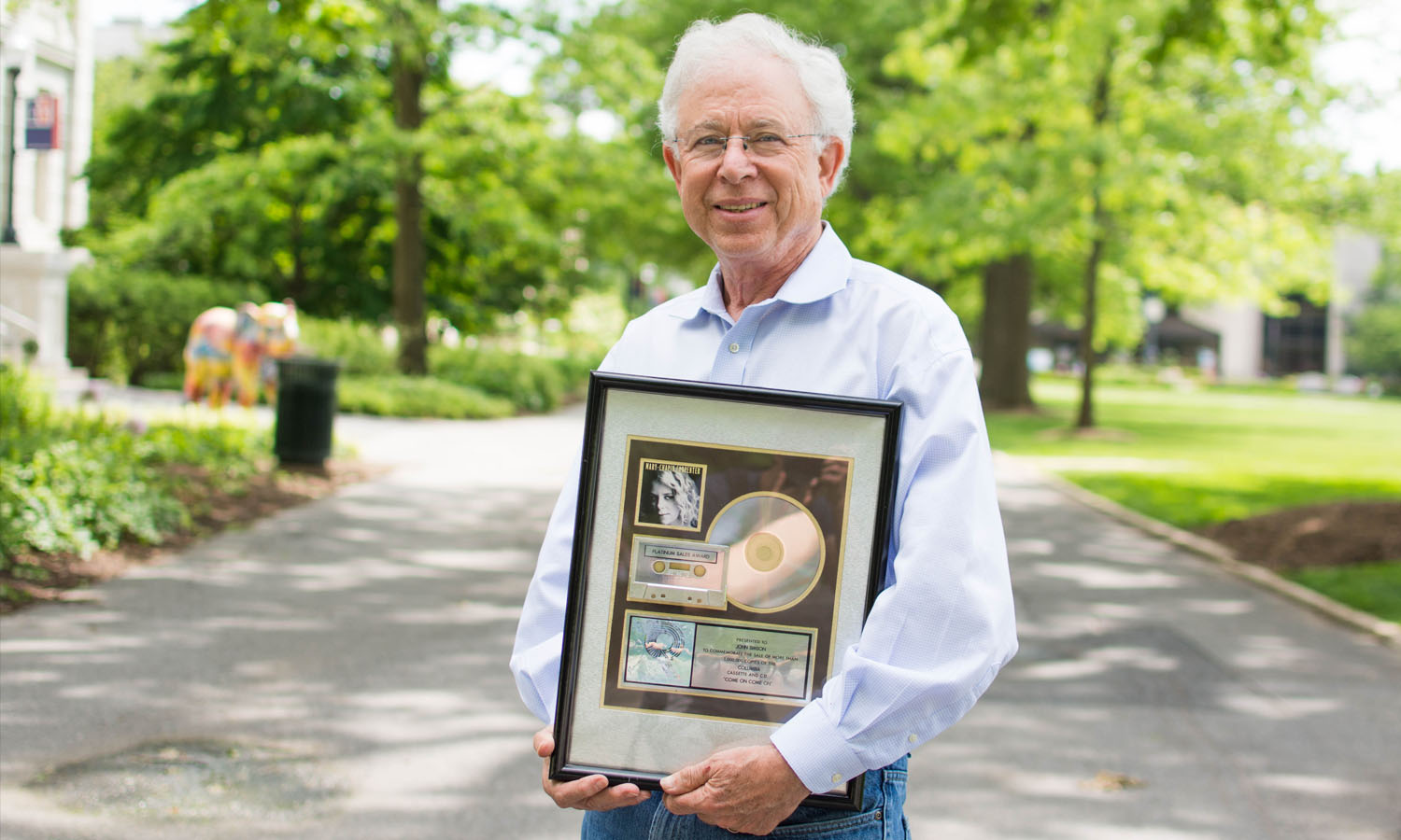 Professor John Simson holding a Platinum sales award